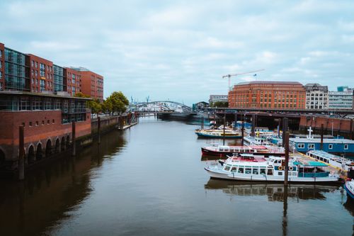 Free A vibrant view of Hamburg harbor featuring boats, modern architecture, and bridges. Stock Photo