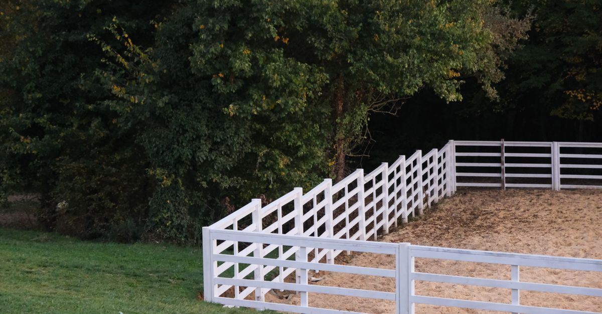 A fenced paddock with white rails, representing the boundaries of a candle's range in CRT trading