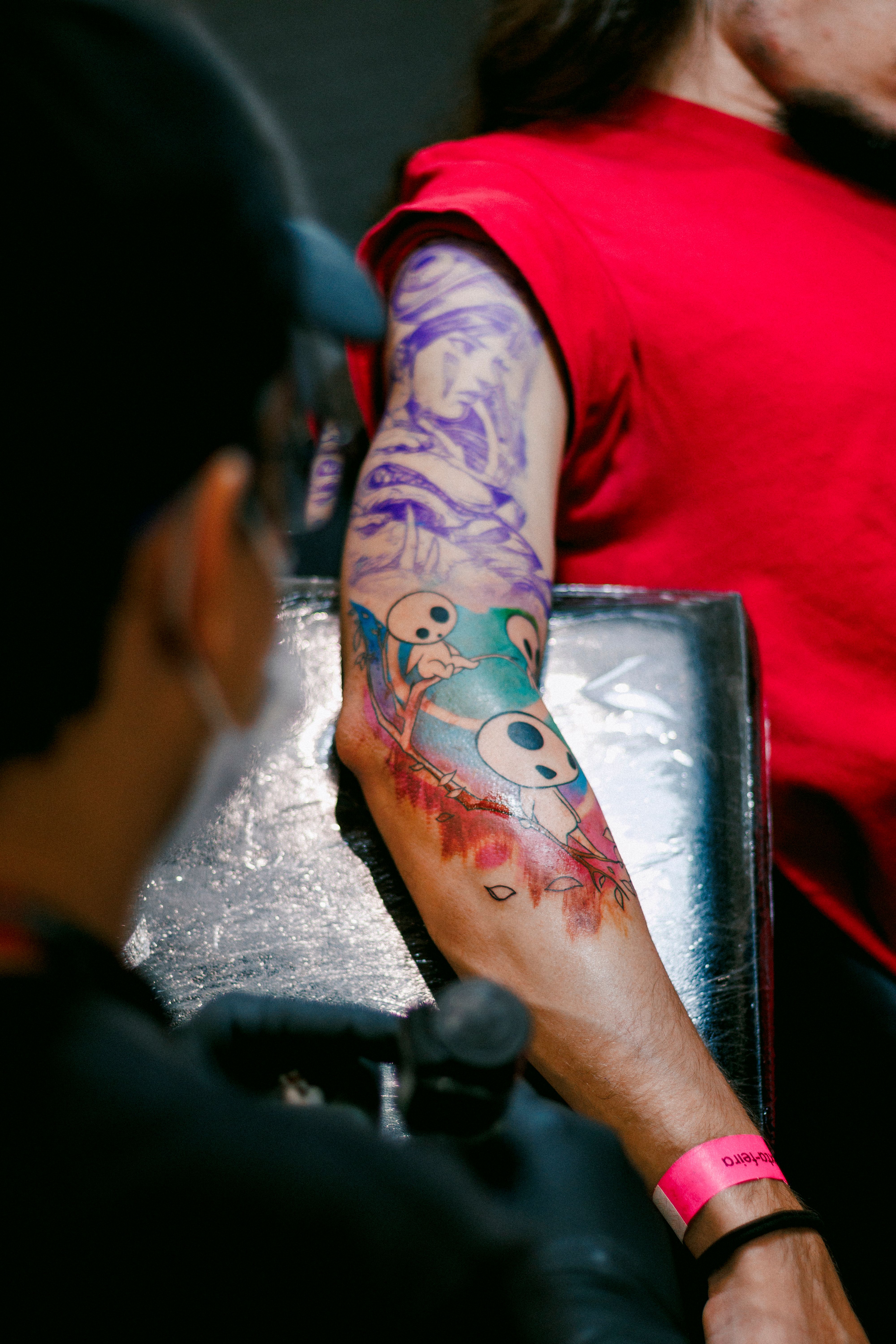 Close-up of a colorful arm tattoo being crafted in a tattoo studio.