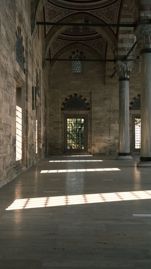 Free Sunlight streaming through a historic mosque's interior, highlighting columns and arches. Stock Photo