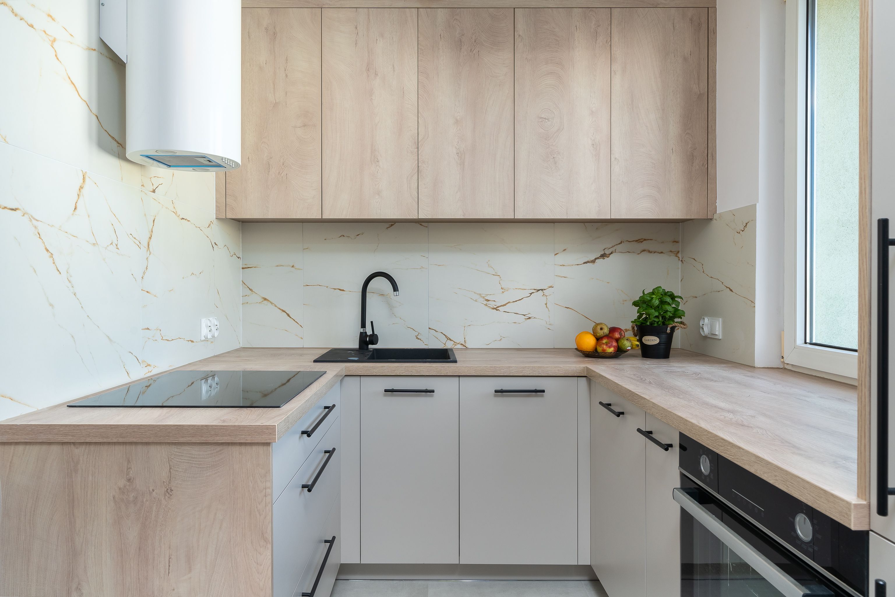 Stylish kitchen interior featuring wooden cabinetry, marble backsplash, and a sleek design.