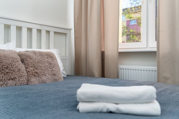Folded white towels laid on a blue bedspread in a bright room — photo by Mateusz Pielech on Pexels