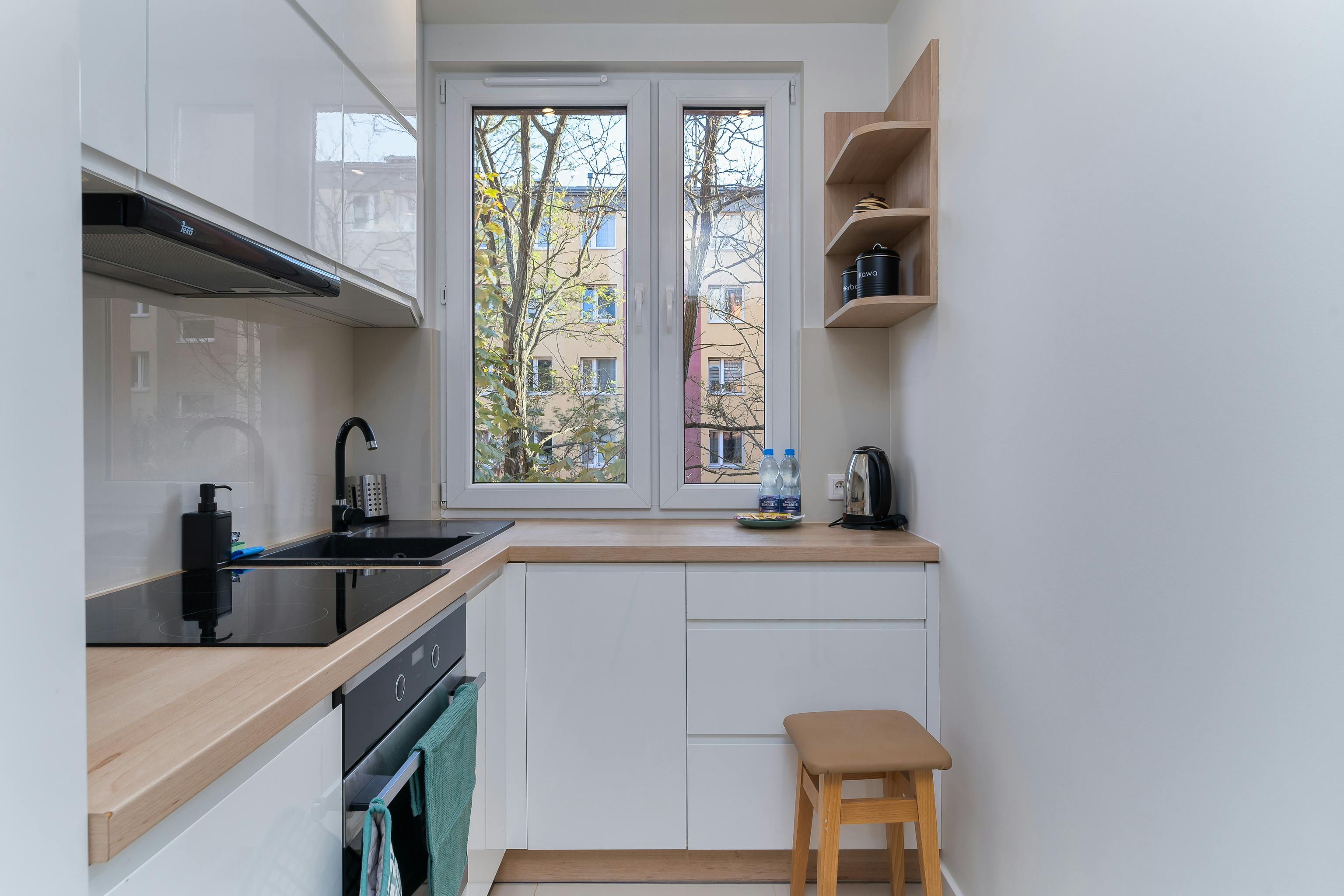 Compact and modern kitchen with sleek white cabinets and natural light.
