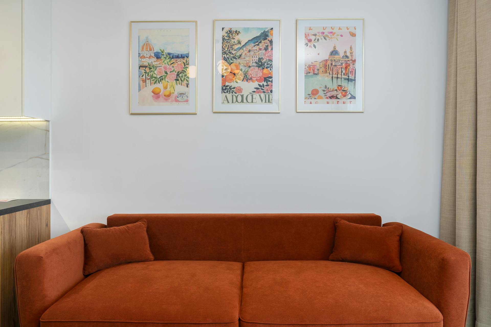 A cozy living room featuring a red sofa and decorative framed art prints on the wall.