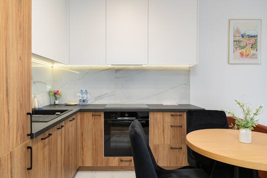 Sleek modern kitchen interior featuring wood cabinets, marble backsplash, and round dining table.