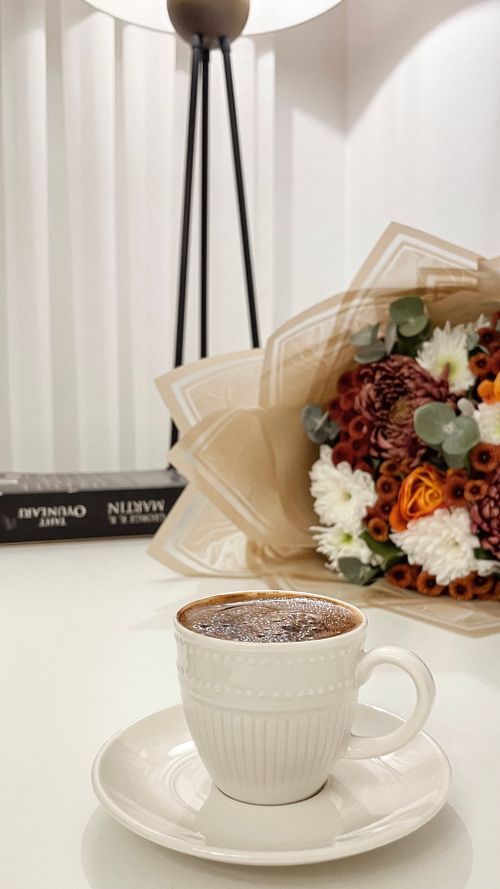 Free Elegant scene of a coffee cup and flower bouquet on a table. Stock Photo