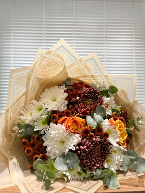 Free Colorful bouquet featuring chrysanthemums, roses, and daisies wrapped elegantly. Stock Photo