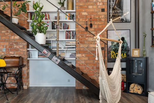 Cozy industrial loft interior featuring a hammock, modern staircase, brick wall, and bookshelf.. pexels, cozy, industrial