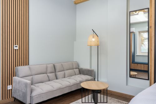 Free Stylish living room with a gray sofa, wooden decor, and warm lighting. Stock Photo