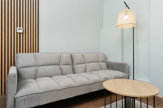 Contemporary living room featuring a grey sofa, wooden accents, and a woven lamp for a minimalist look.