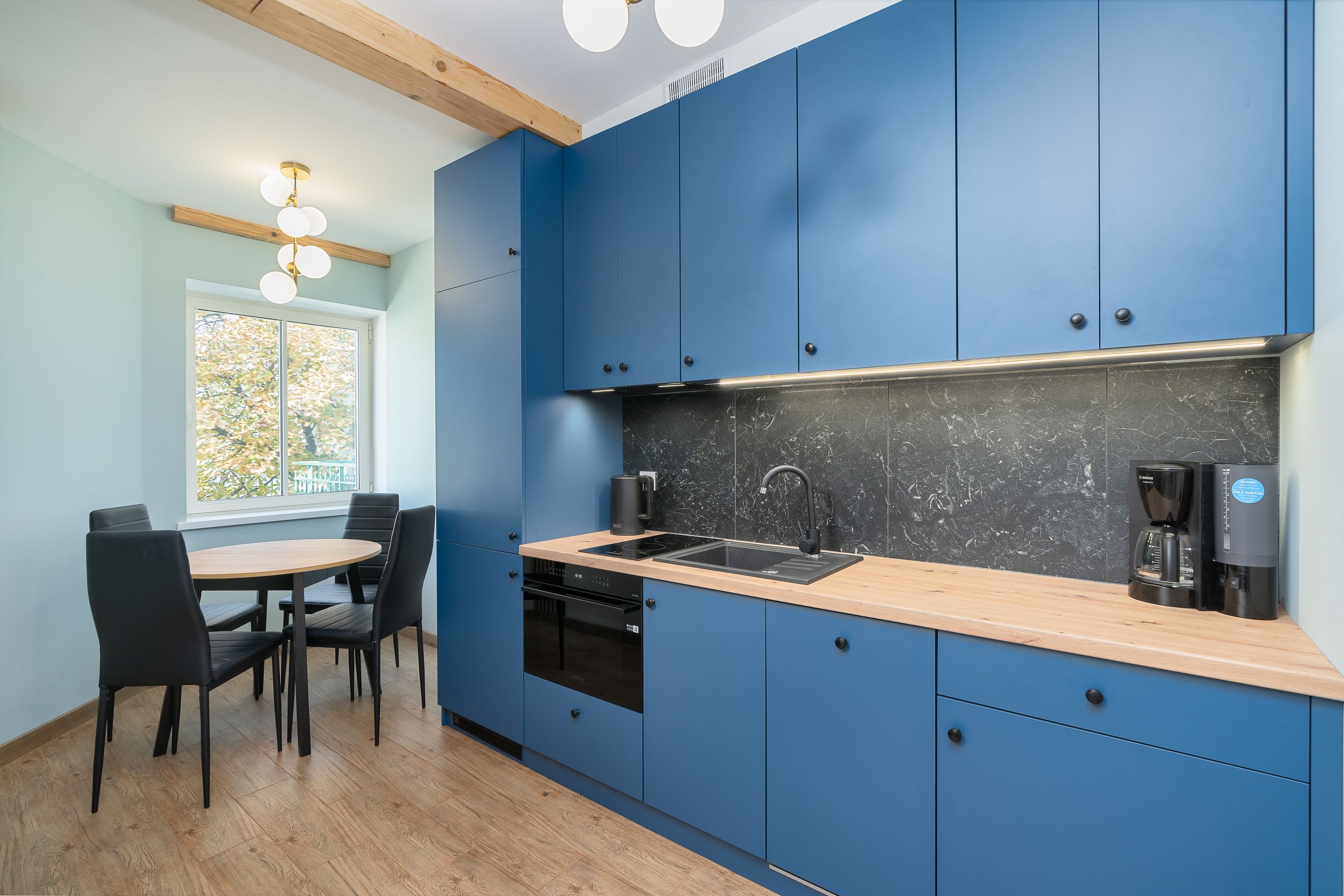 Blue cabinetry beside a light dining area in an open apartment