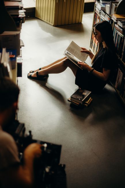 A young woman enjoys reading in a dimly lit bookstore, creating a cozy atmosphere.