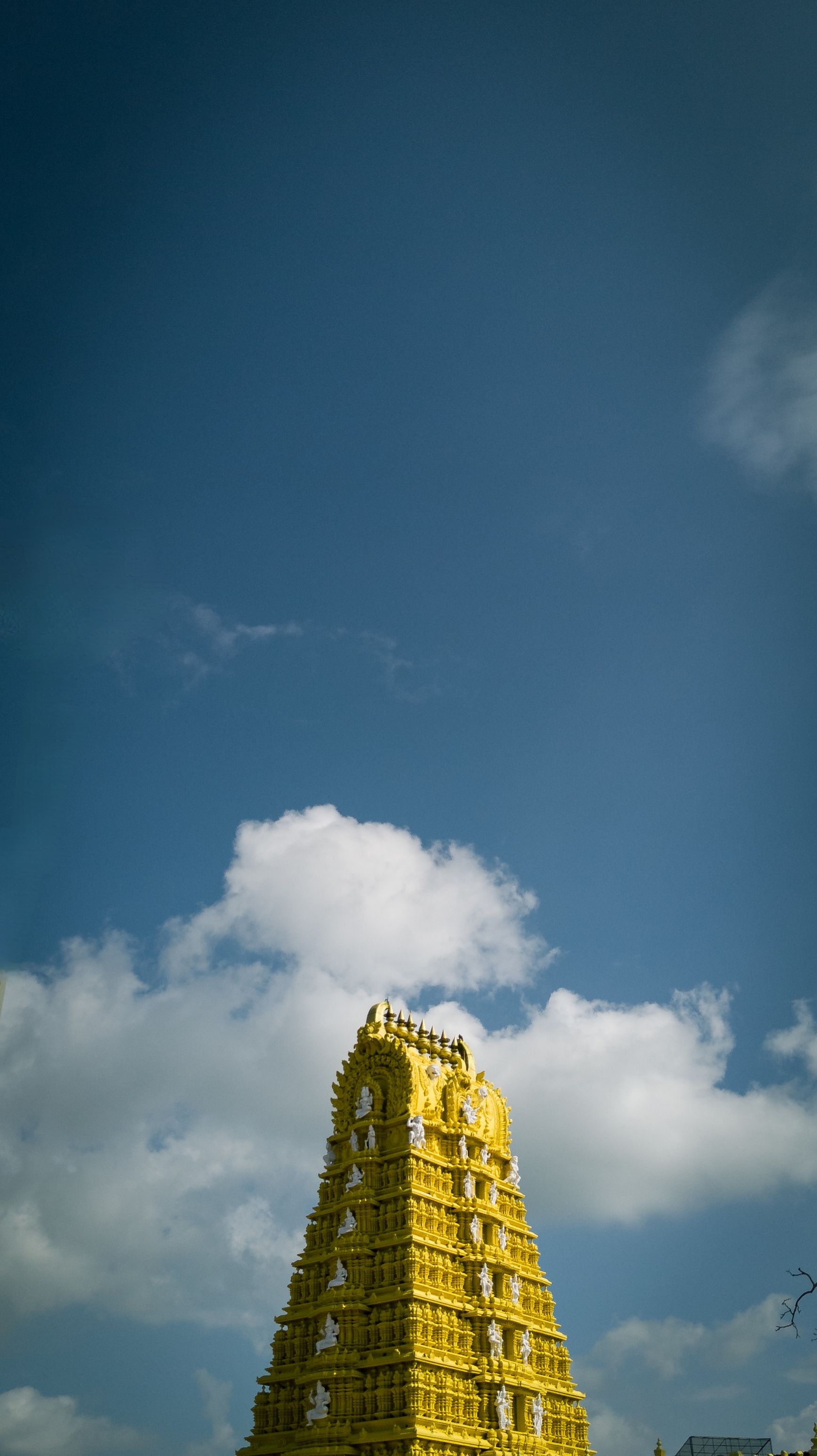 Stunning view of a Dravidian style gopuram under a vivid blue sky in Mysuru, India.