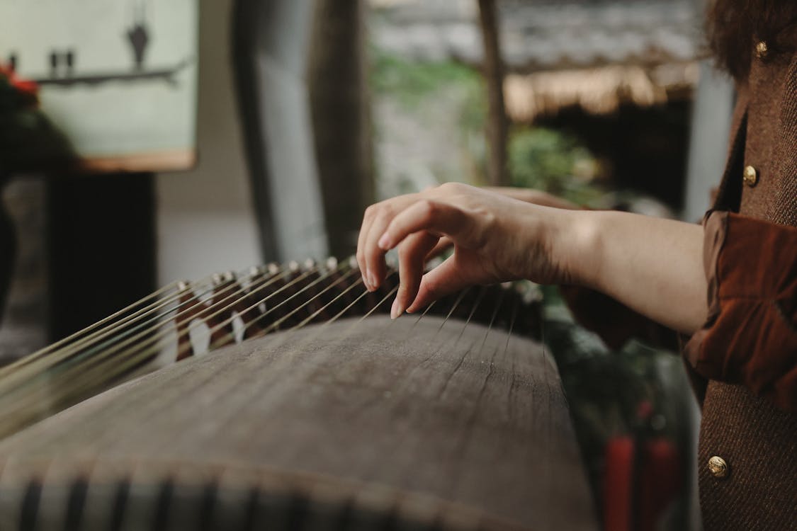 Free Hands playing a Guzheng instrument, showcasing traditional music in an intimate setting. Stock Photo