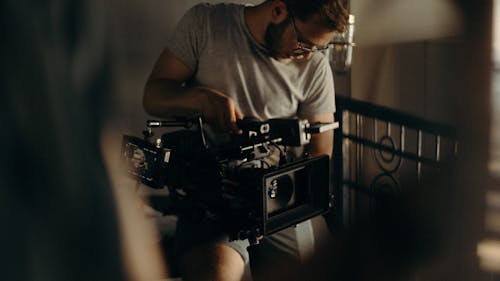 Мужчина в серой футболке с круглым вырезом с фотоаппаратом