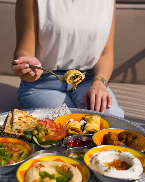 Free A person enjoying a variety of Middle Eastern dishes outdoors. Fresh, vibrant, and delicious. Stock Photo