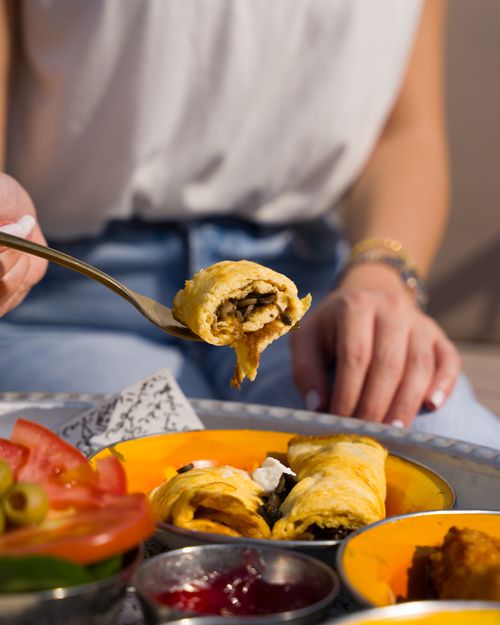 Free A person enjoying an omelette with fresh tomatoes and olives on a sunny morning. Stock Photo