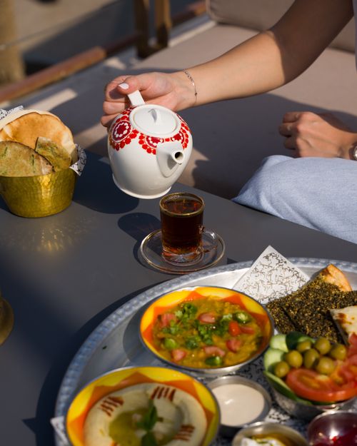 Free A Middle Eastern breakfast with tea, hummus, and bread on a table outdoors. Stock Photo
