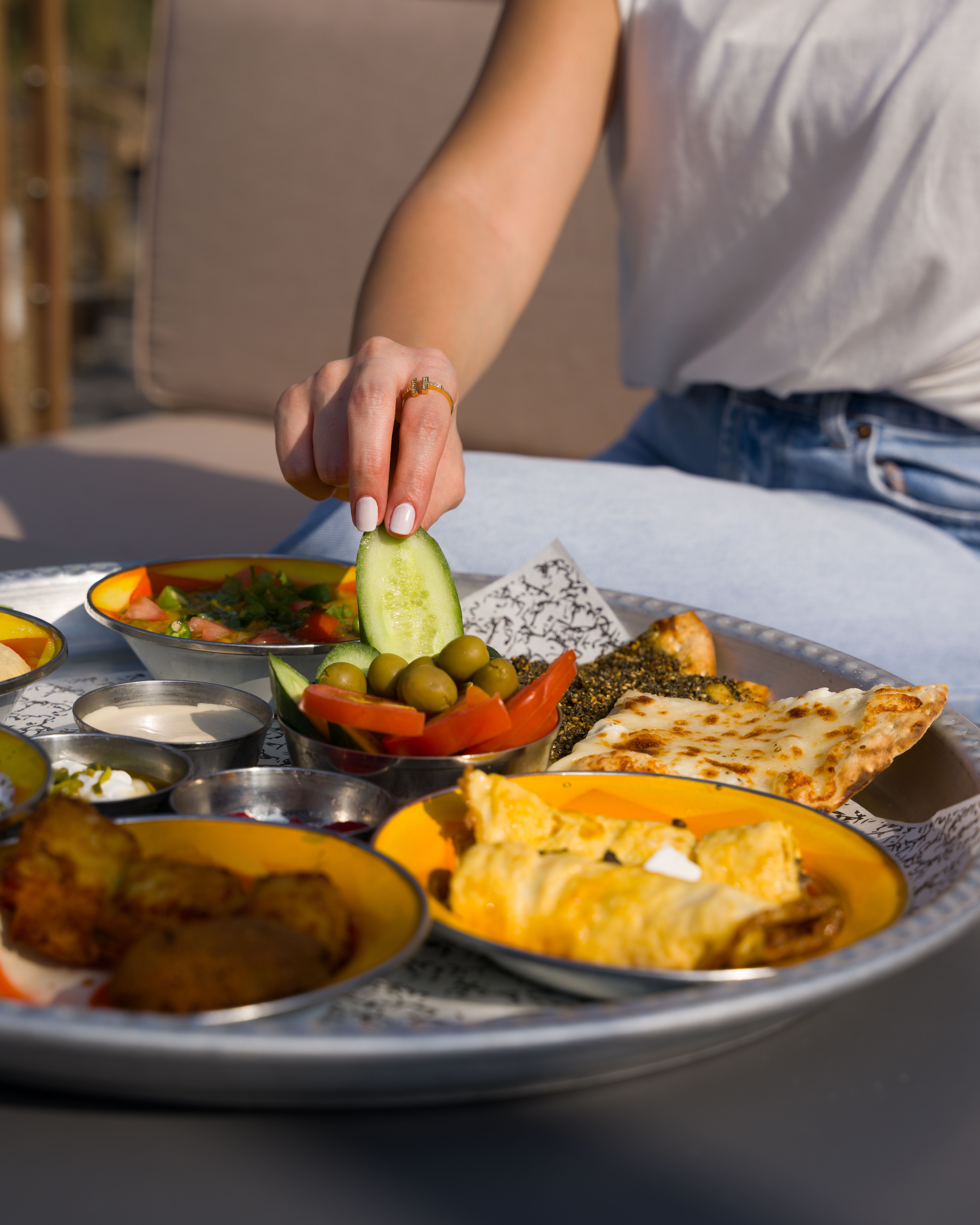 Close-up of a diverse Mediterranean breakfast with olives and vegetables outdoors.
