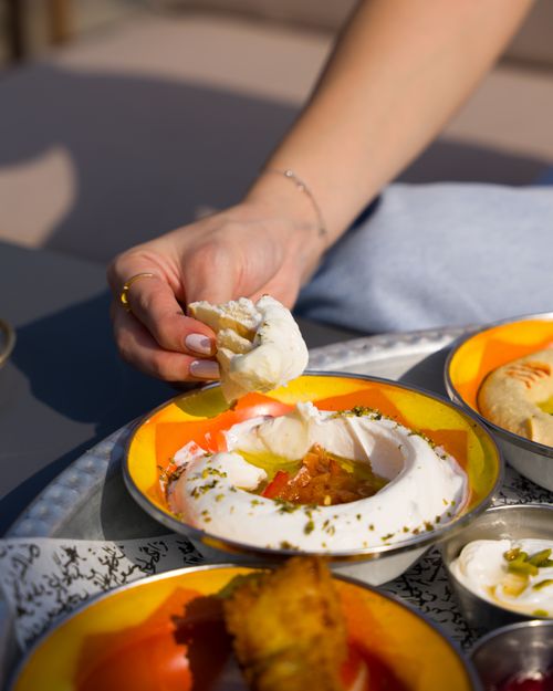 Free Hand dipping bread into vibrant Middle Eastern hummus plate. Stock Photo