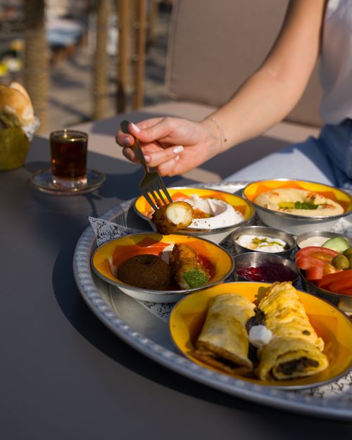 Free Outdoor breakfast setting featuring Middle Eastern dishes on colorful plates and tea. Stock Photo
