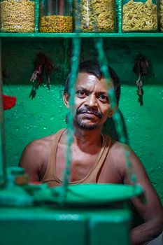 Man in colorful market with jars of grains, vibrant atmosphere.