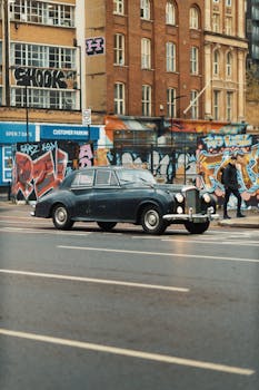 Classic car on a vibrant graffiti-lined street in an urban setting, capturing street art culture.