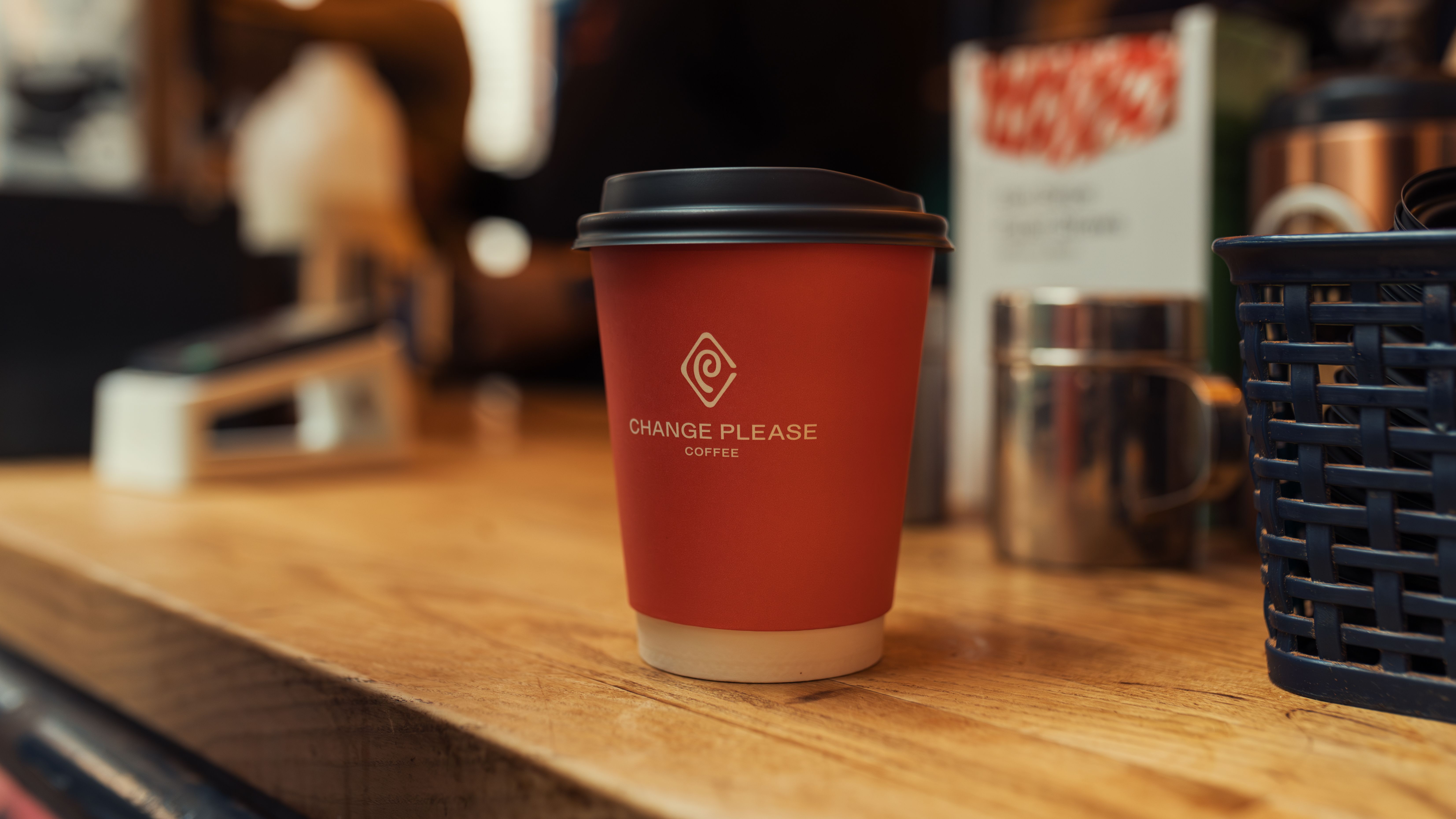 A coffee cup on a wooden counter inside a small café.