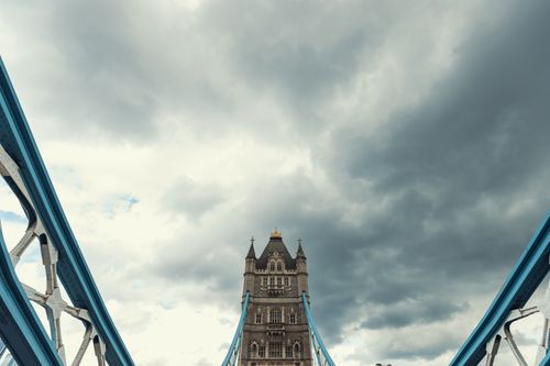 Free View of Tower Bridge in London with a dramatic cloudy sky overhead, highlighting its iconic architecture. Stock Photo