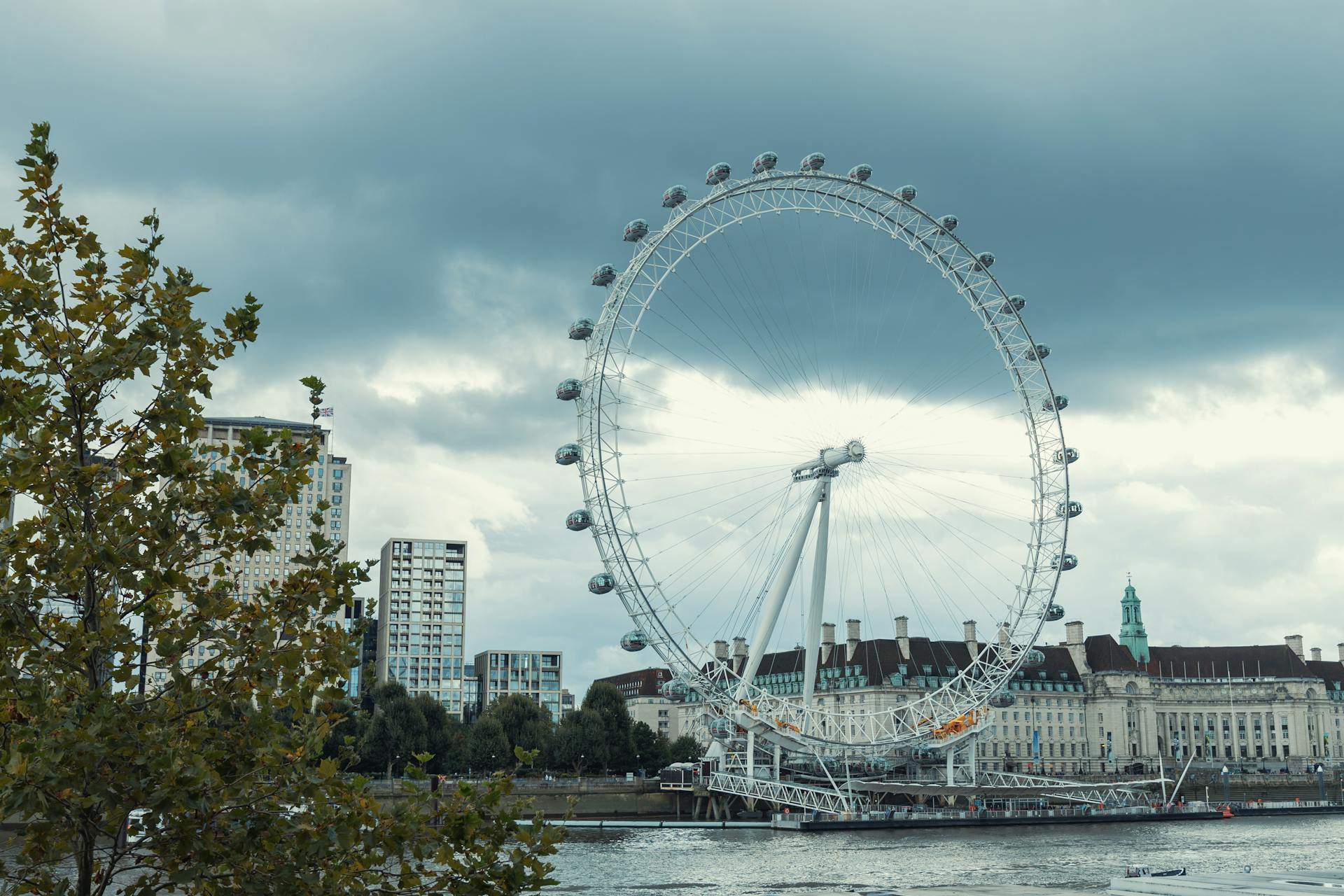 View of the London Eye and South Bank under a cloudy sky, showcasing vibrant cityscape.