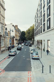 A serene urban street scene featuring parked cars and classic architecture on a quiet afternoon.