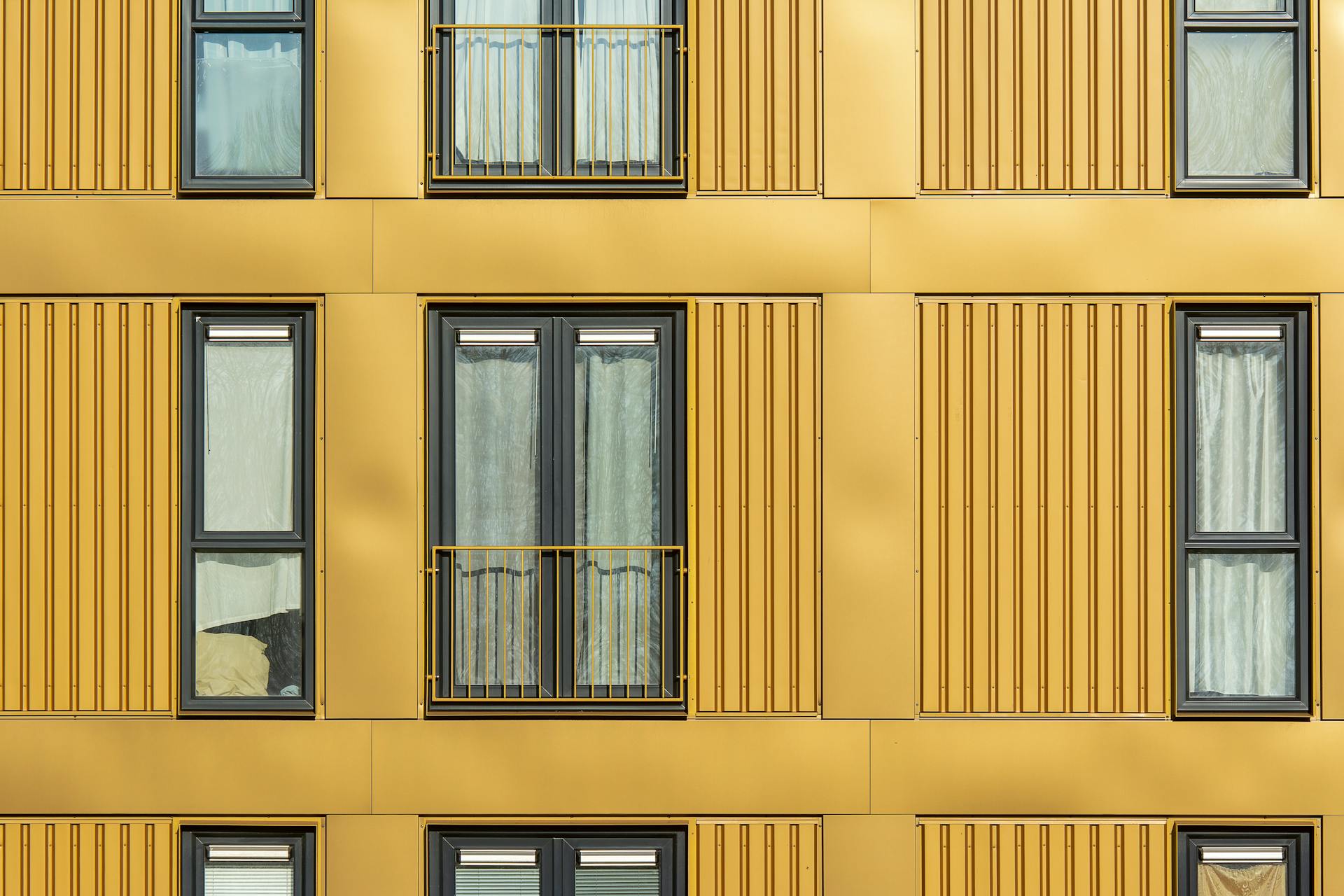 Geometric yellow facade with windows and balconies in urban architecture.