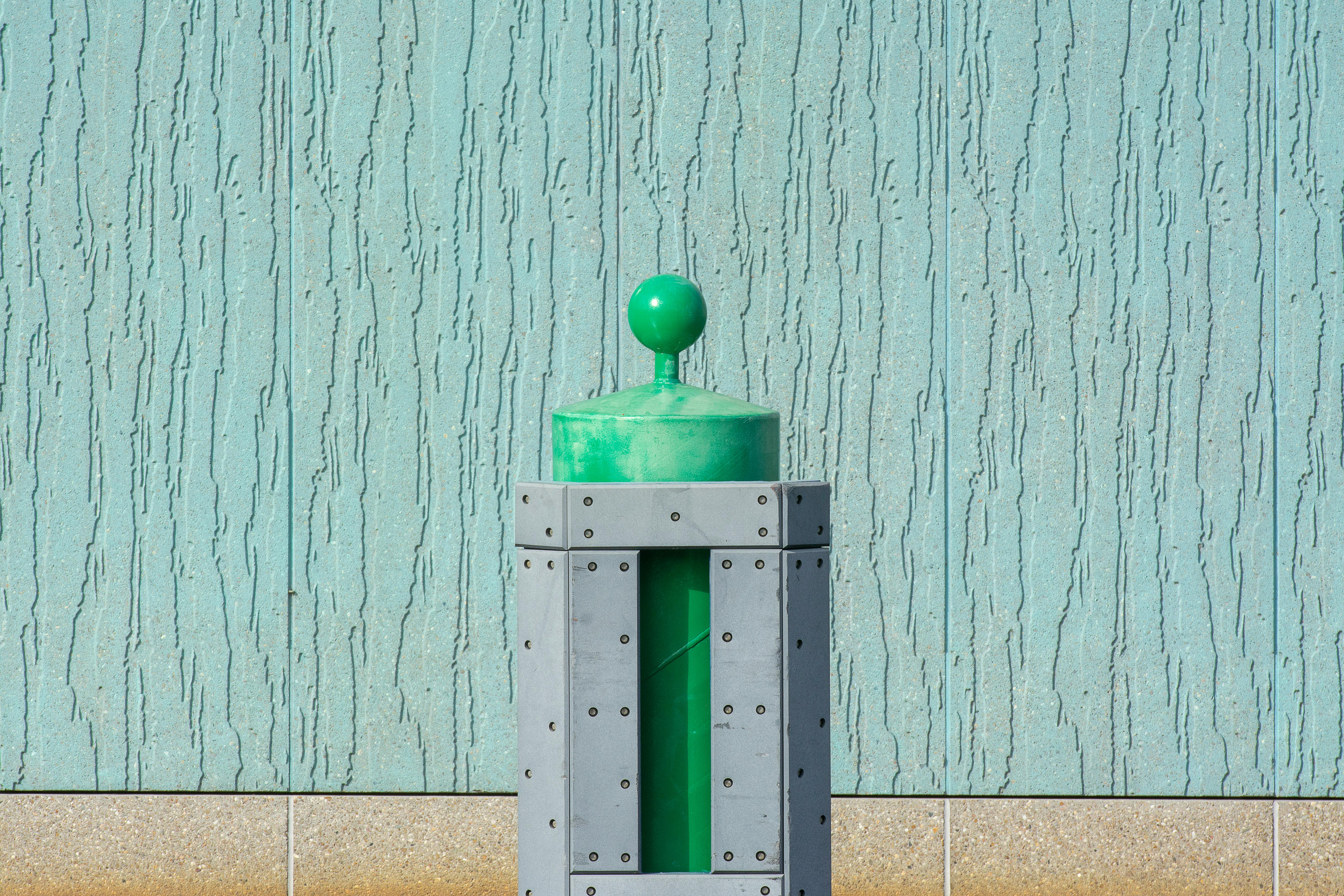 Free Green post in front of a blue textured wall, minimalistic style. Stock Photo