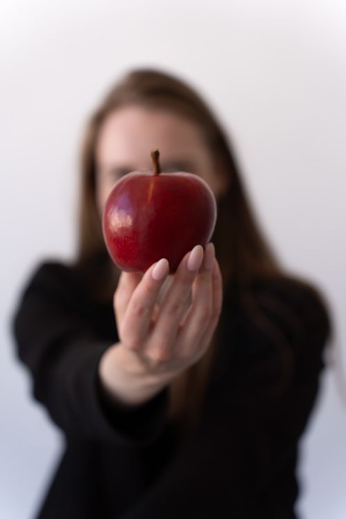 Free A woman in black offers a red apple, symbolizing temptation and health. Stock Photo