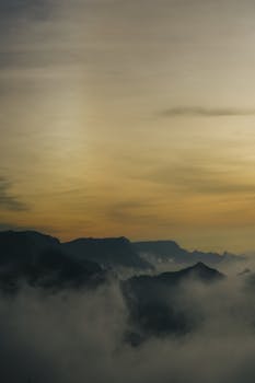 Ethereal sunrise view with misty mountains and a vibrant sky.