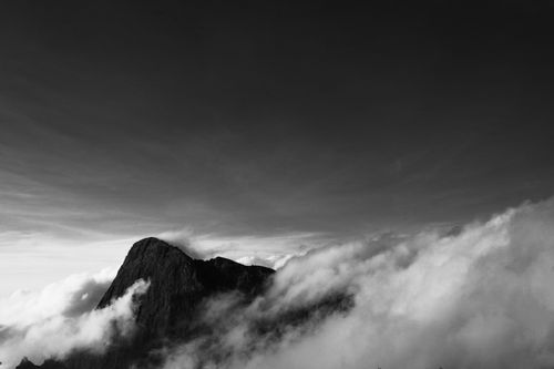 Free A striking black and white image of a lone mountain peak surrounded by clouds, evoking mystery and grandeur. Stock Photo