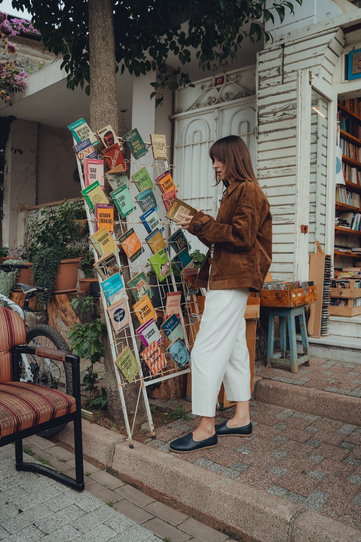 A woman browsing an outdoor book stand in autumn, wearing flats — the ease of the flat shoe