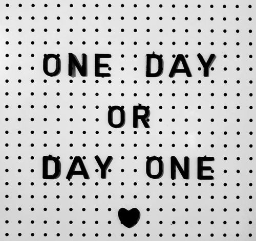 Free Black letters on white board saying 'One Day or Day One?' with polka dot design. Stock Photo