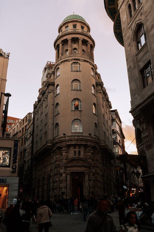 Free A historic building stands tall in a busy city street at sunset, capturing urban life and architecture. Stock Photo