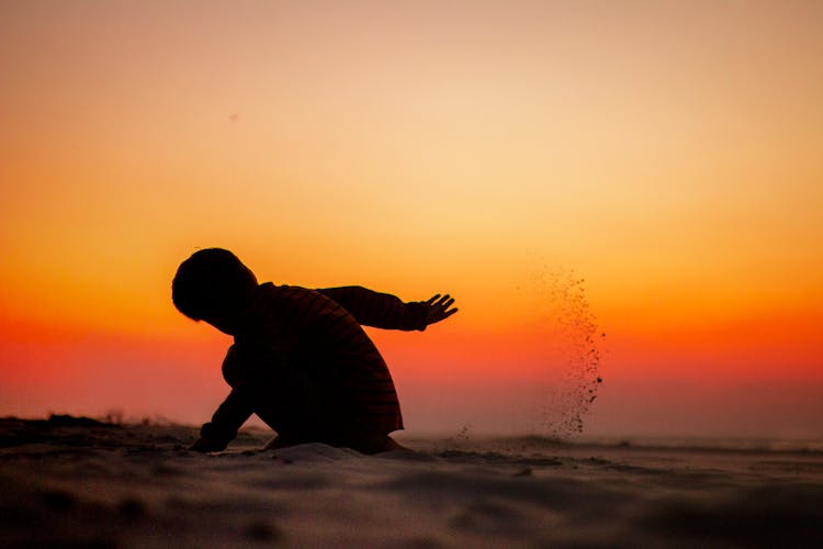 Silhouette Of A Child Playing On Sands