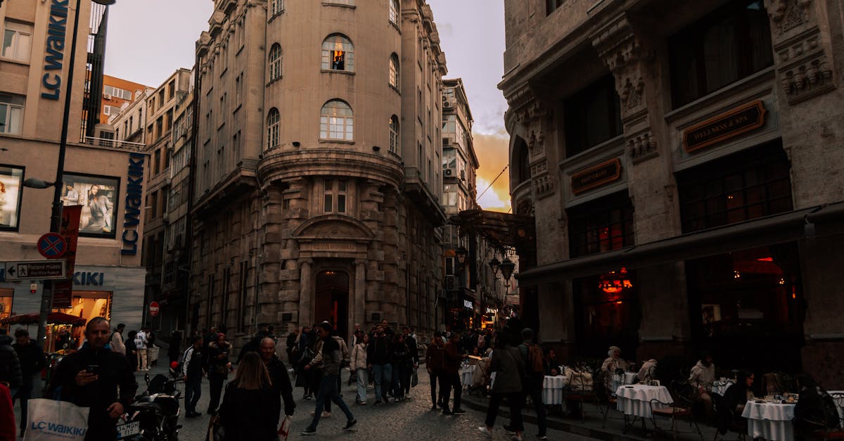 Photo by Ömer Derinyar Urban street scene during twilight with people walking and dining outdoors in a European city.