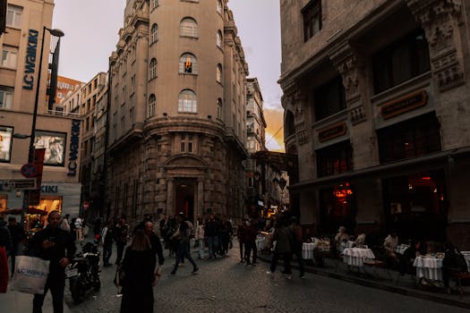 Photo by Ömer Derinyar Urban street scene during twilight with people walking and dining outdoors in a European city.