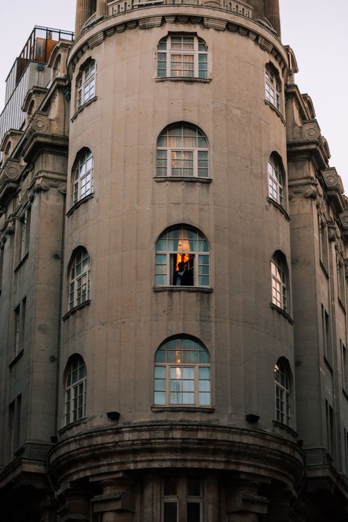 Free Vintage building facade with a warmly lit window indicating life inside. Stock Photo
