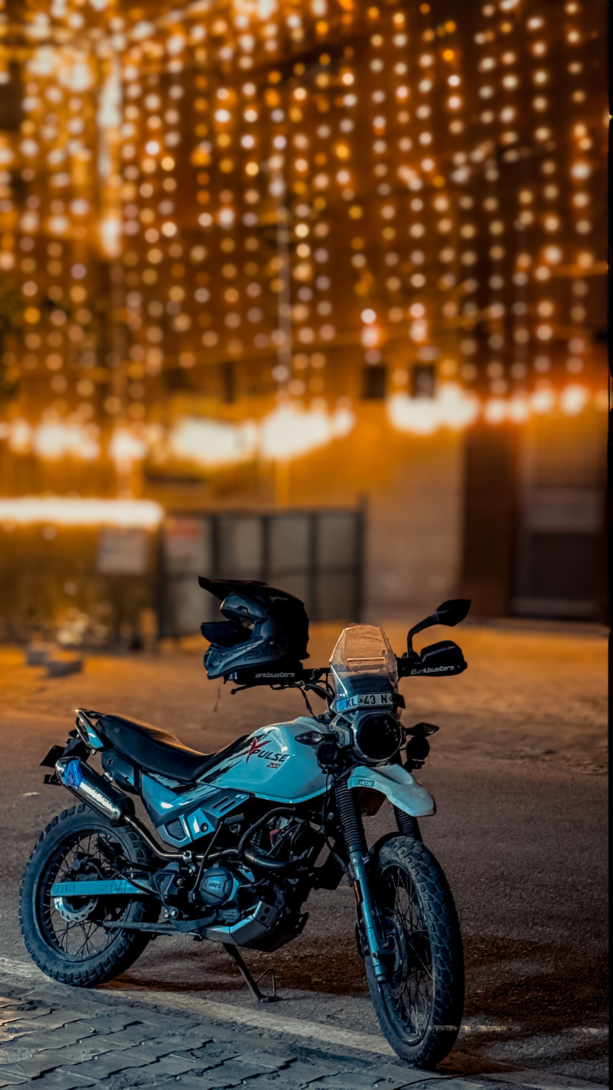 Motorcycle parked beneath glowing festive lights in Gurugram, creating a vibrant nighttime scene.