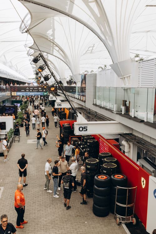 Free A bustling Formula 1 pit lane with crew, tires, and visitors under a modern roof. Stock Photo