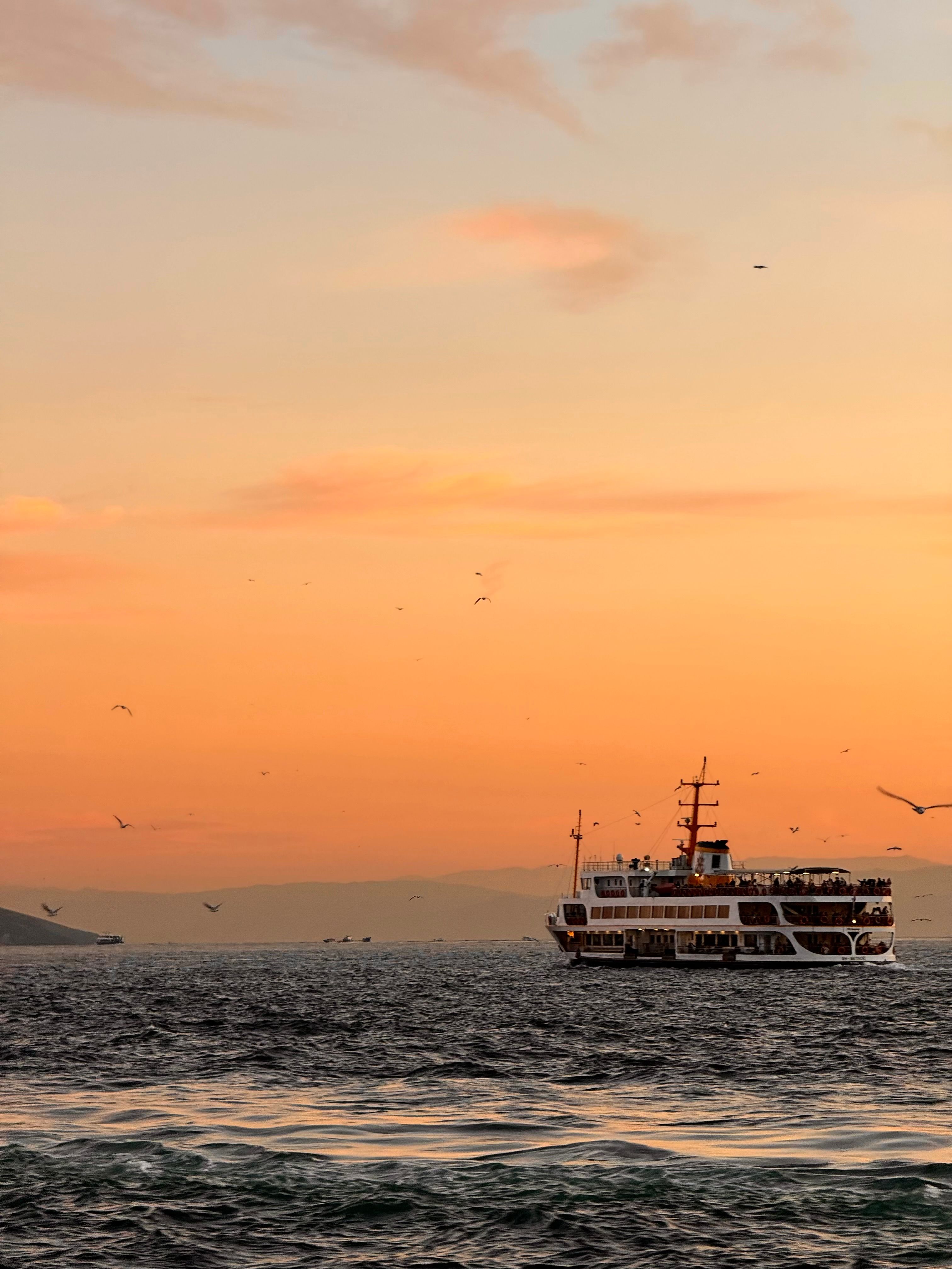 A serene ferry voyage across the Bosporus in İstanbul during sunset, capturing vibrant skies and tranquil seas.