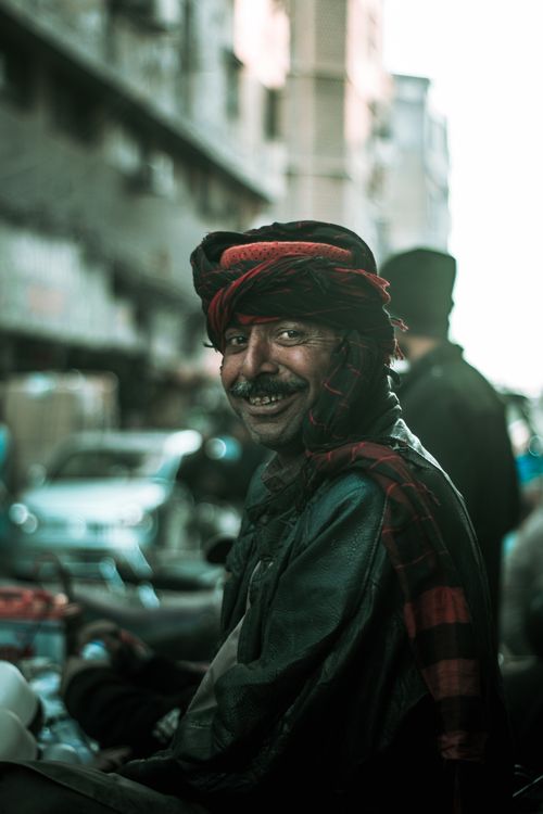 Free Portrait of a smiling man in traditional attire on a busy street. Stock Photo