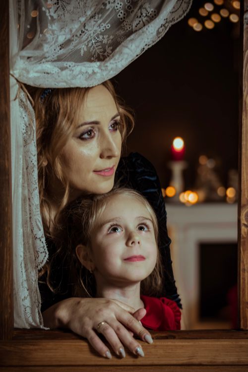 Free A mother and daughter share a tender moment by candlelight, creating a warm festive atmosphere. Stock Photo
