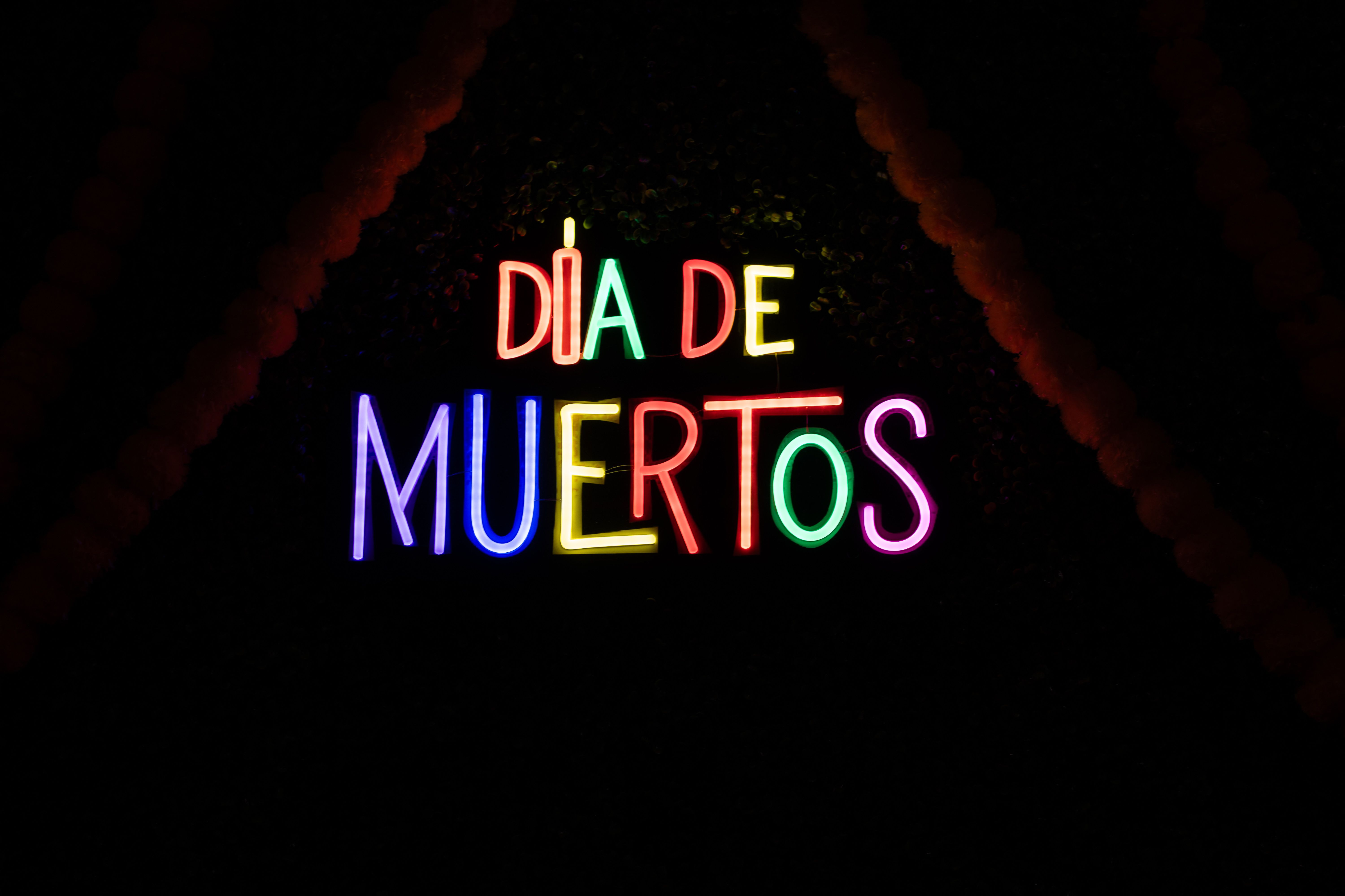 Colorful neon sign celebrating Dia de Muertos at night in Atlanta.