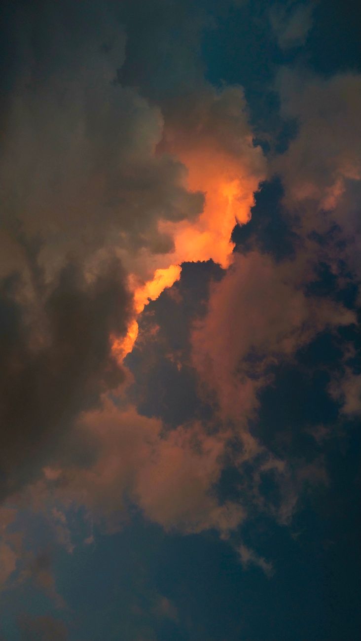 Capture of a dramatic sky with glowing clouds at sunset, creating a moody atmosphere.